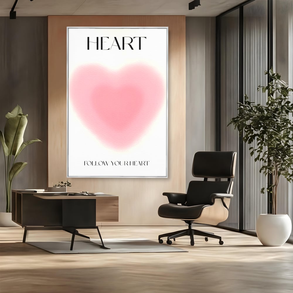 Tablou canvas cu tablou vertical cu inima roz blurata, in rama de aluminiu argintiu, pe perete intr-un birou